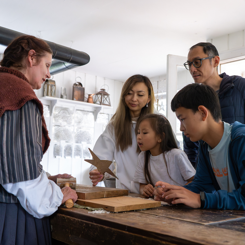 a home school group at The Village at Black Creek learns how the local tinsmith creates traditional holiday ornaments