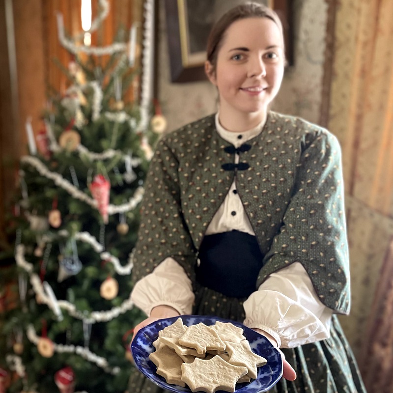 Holidays at The Village 14 a costumed educator offers shortbreads to visitors attending the Santa at the Village event at The Village at Black Creek