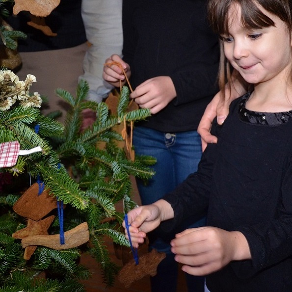 Holidays at The Village 11 a home school student places a handmade ornament on a Christmas tree at the Village at Black Creek
