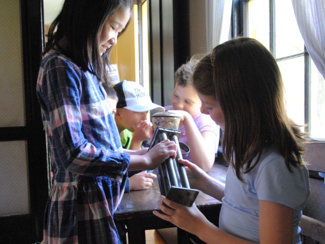 children examine objects in the building at the Village at Black Creek