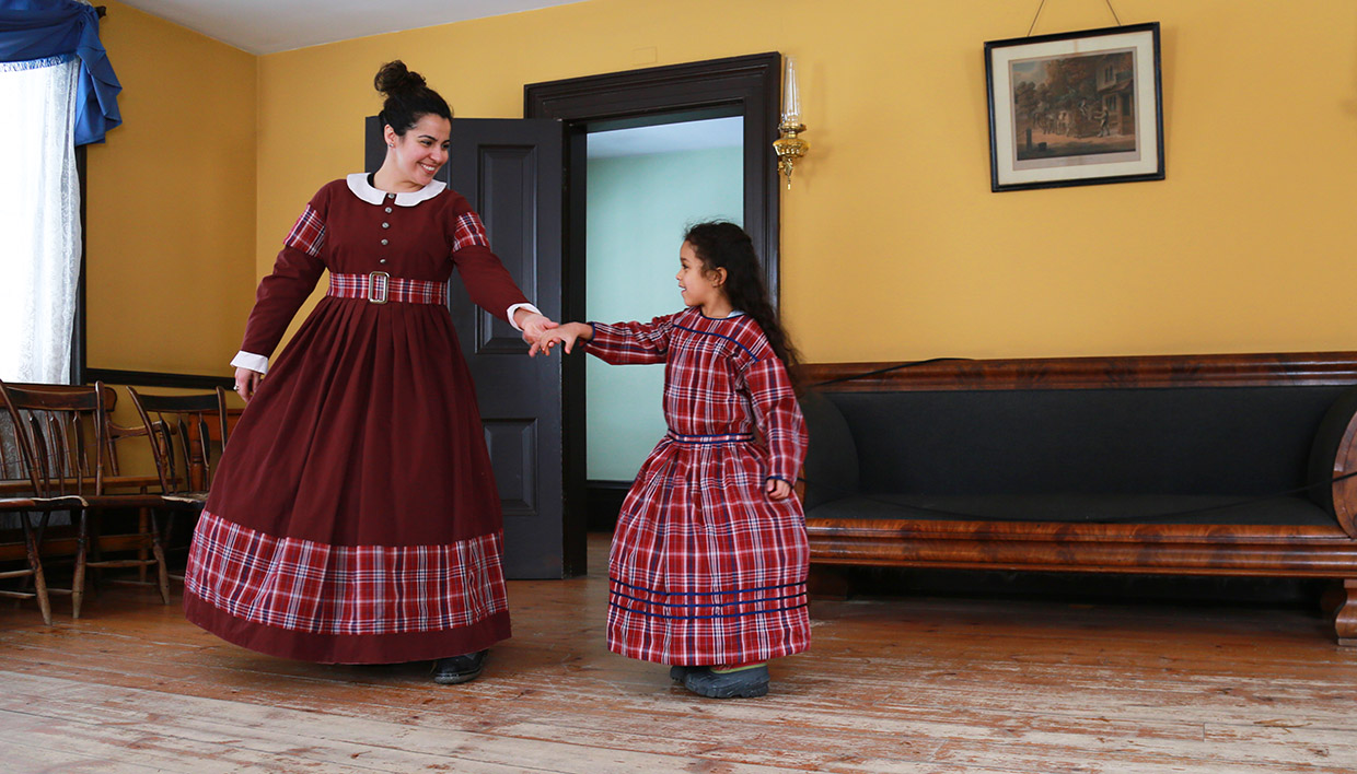a woman and a young girl model pioneer dresses at a Black Creek Pioneer Village Discovery Station